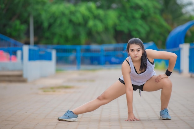 Donna sportiva asiatica che allunga il corpo respirando aria fresca nel parcoLa gente della Thailandia Concetto di fitness ed esercizio Jogging in pistaLe ragazze grasse vogliono dimagrire