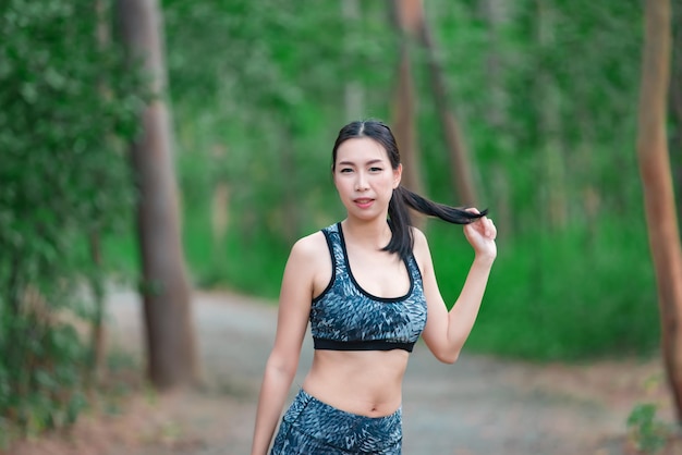 Donna sportiva asiatica che allunga il corpo respirando aria fresca nel parcoThailandia personeFitness e concetto di esercizio Jogging nel parcoRiscaldare il corpo