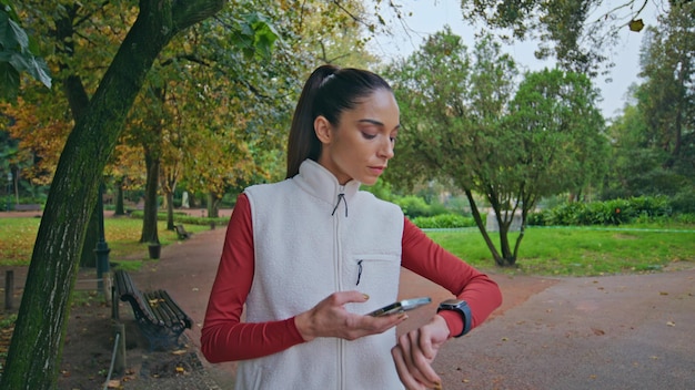 Donna sportiva che controlla lo smartwatch nel parco che si prepara per un primo piano di fitness