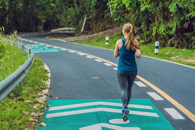 Donna sportiva che corre su strada all'alba fitness e allenamento benessere concept