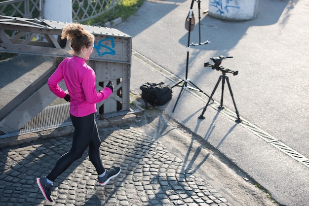 donna sportiva che corre sul marciapiede al mattino presto jogging con la scena dell'alba della città sullo sfondo