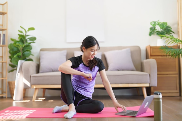 Donna sportiva che digita sul laptop per guardare l'allenamento di yoga online e fare esercizio per lo yoga a casa