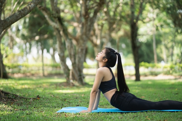 Donna sportiva che fa esercizio di yoga all'aperto nel parco, concetto di yoga sportivo