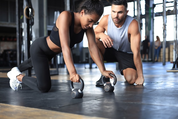 Donna sportiva che fa flessioni in palestra, il suo ragazzo la sta guardando.