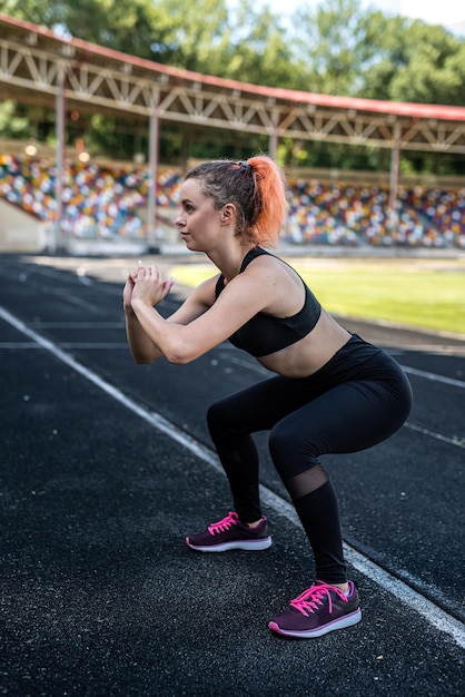 Donna sportiva che fa stretching o esercizio di yoga sulla pista dello stadio. concetto di flessibilità