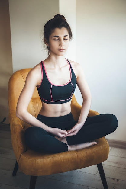 donna sportiva che indossa abbigliamento sportivo sta meditando sulla poltrona con gli occhi chiusi