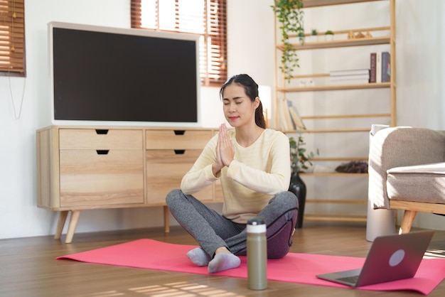 Donna sportiva che medita per praticare l'esercizio di yoga mentre fa la posizione del loto yoga con la posa del namaste