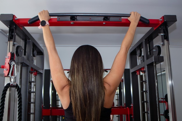 Donna sportiva che si esercita su multi-stazione in palestra per i muscoli delle braccia e delle spalle Fitness che si esercita in palestra