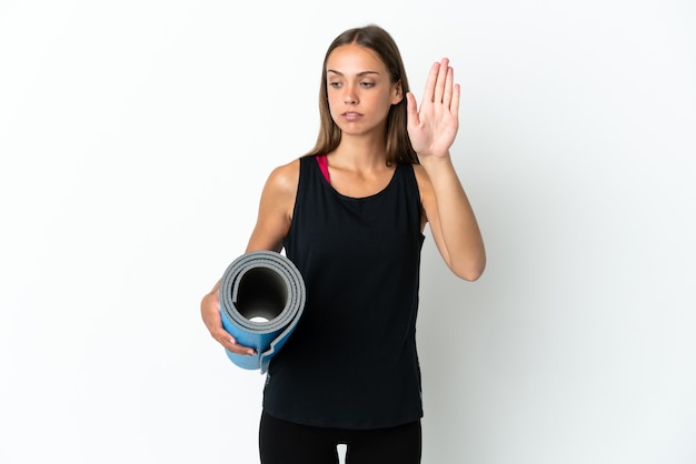 Donna sportiva che va alle lezioni di yoga mentre tiene un tappetino isolato