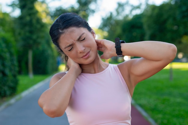 Donna sportiva con il dolore al collo all'aperto