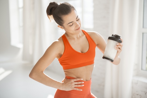 Donna sportiva con shaker di proteine in palestra