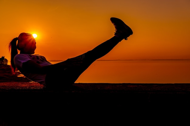 Donna sportiva della siluetta con il tramonto. Attività sana e di esercizio. Stile di vita e ricreazione.