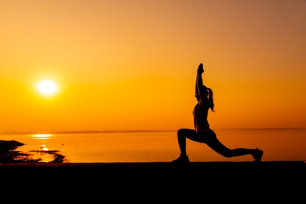 Donna sportiva della siluetta con il tramonto. Attività sana e di esercizio. Stile di vita e ricreazione.