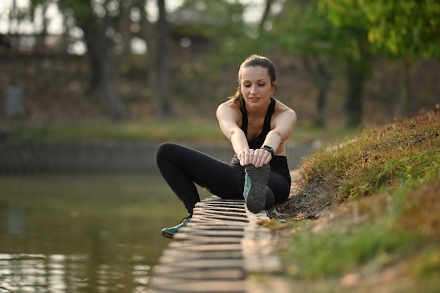 Donna sportiva Donna sportiva che allunga esercizi vicino al lago Stile di vita sano concetto di sport e fitness