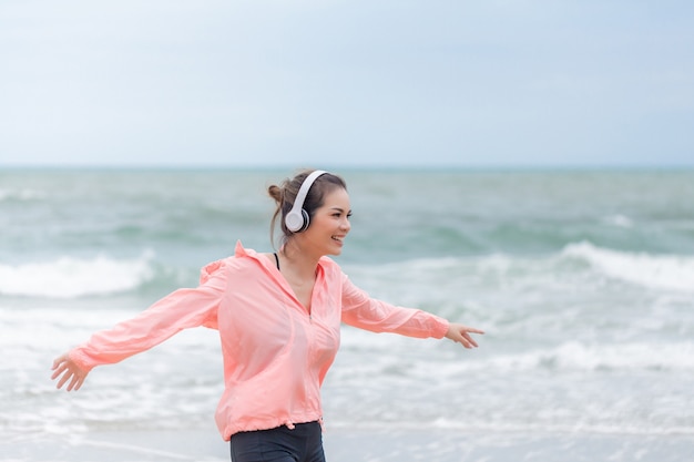 Donna sportiva felice che corre sulla spiaggia con un bel sorriso