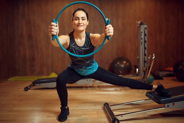 Donna sportiva in abbigliamento sportivo, allenamento pilates con anello sulla macchina ginnica in palestra. Workuot fitness nel club sportivo.