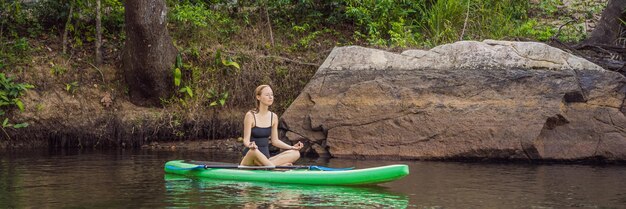 Donna sportiva in posizione yoga sul paddleboard che fa yoga sull'esercizio della tavola sup per flessibilità e