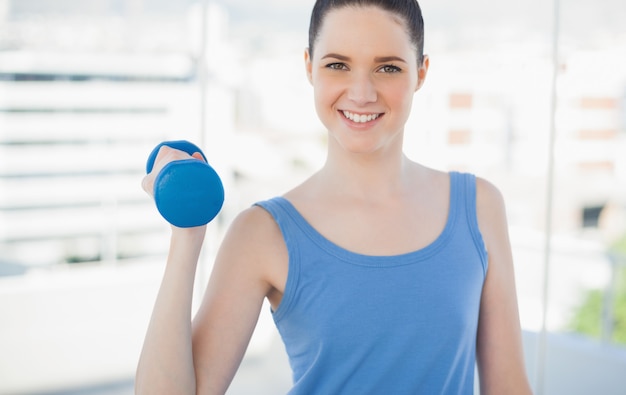 Donna sportiva sorridente che si esercita con il dumbbell