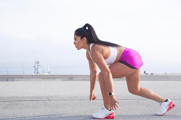 Donna sportiva vestita di abbigliamento sportivo pronta per iniziare a fare jogging in città