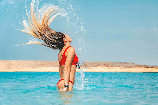 Donna spruzzi d'acqua con i capelli in oceano Messa a fuoco selettiva Capelli in motion blur