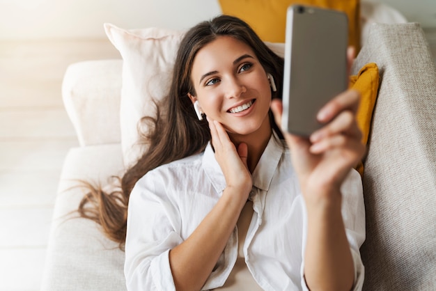 donna sta riposando a casa, utilizza lo smartphone per comunicare con gli amici, controlla la posta elettronica.