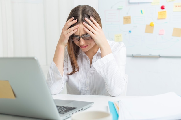 Donna stanca al lavoro al computer. Mal di testa.