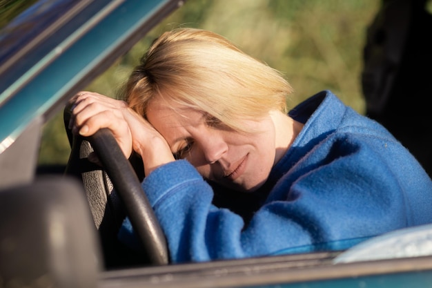 Donna stanca alla guida di un'auto Una donna di mezza età sulla quarantina si sporse sul volante di un'auto Riposo per stanchezza durante il viaggio