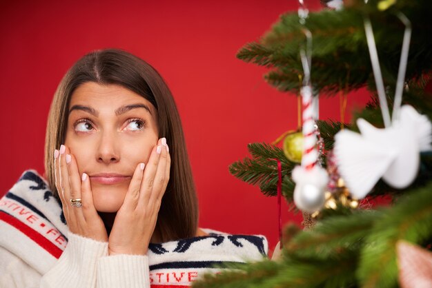 donna stanca che decora l'albero di Natale su sfondo rosso