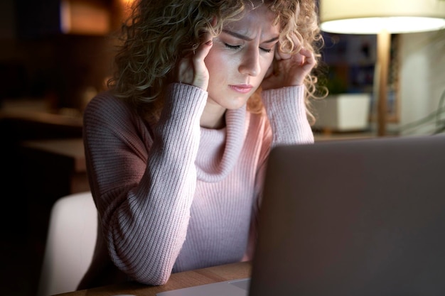 Donna stanca che lavora al computer portatile alla scrivania