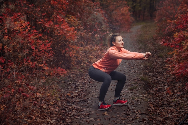 Donna stanca di sport in abiti sportivi nella foresta di autunno