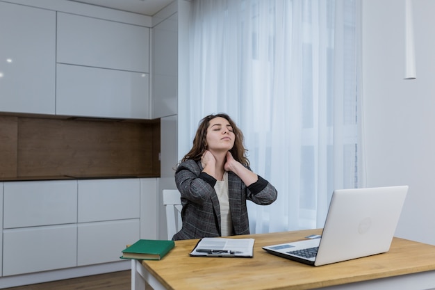 Donna stanca e assonnata che lavora su un laptop, a casa o in ufficio, lavora online