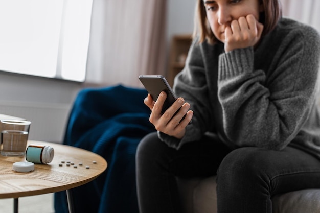 donna stressata con medicine e telefono a casa