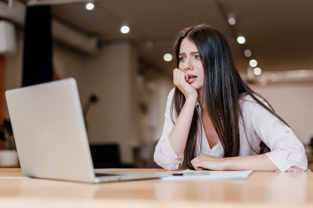 Donna stressata, spaventata e confusa che utilizza computer portatile nell'ufficio