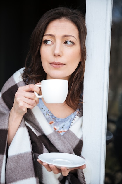 Donna stupefacente che sta all'interno mentre bevendo caffè