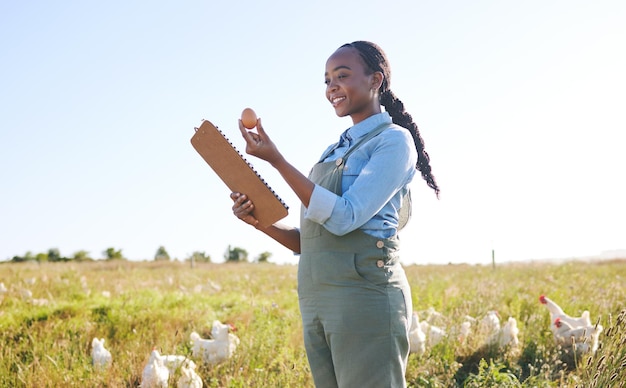 Donna sul campo con appunti di polli e garanzia di qualità delle uova e agricoltura sostenibile per piccole imprese in Africa Lista di controllo per l'ispezione di un allevamento di pollame e agricoltore in campagna con uccelli sull'erba