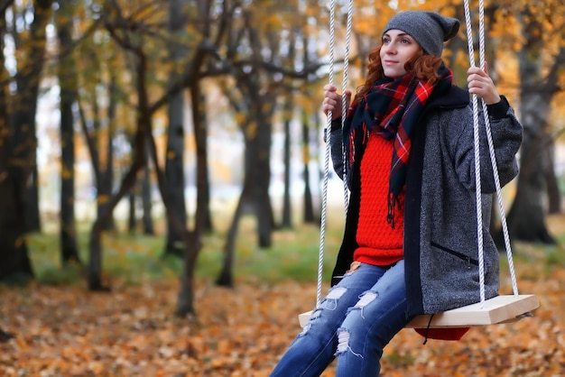 Donna sull'altalena nel parco d'autunno