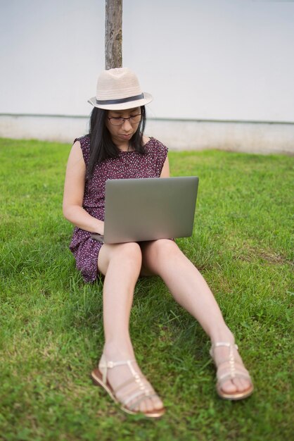 Donna sull'erba che lavora con il laptop