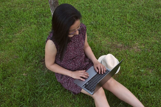 Donna sull'erba che lavora con il laptop