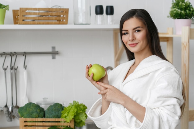 Donna sulla casa della cucina con la cottura delle verdure verdi. Vitamine di dieta domestica sana dell'alimento giovane e bella femmina. Colpo dello studio.