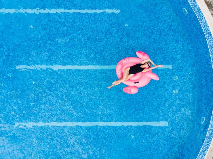 Donna sulla piscina di fenicotteri che galleggia in piscina, vista aerea del drone