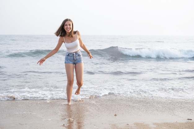 Donna sulla riva della spiaggia felice guardando la fotocamera, orizzontale, copia spazio