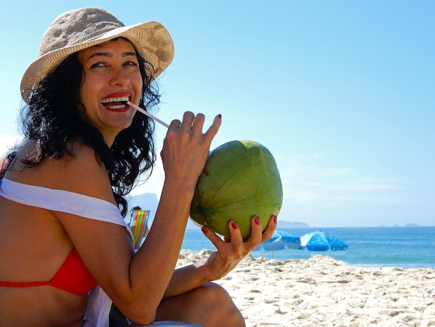 Donna sulla spiaggia che beve acqua di cocco a Rio de Janeiro