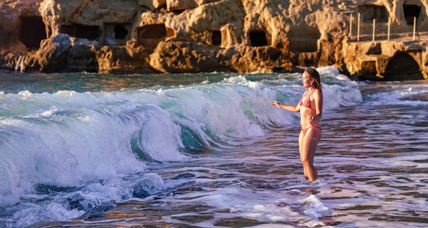 Donna sulla spiaggia che gioca con le onde