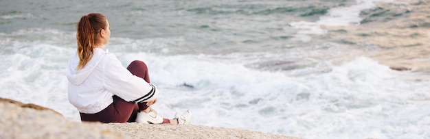 Donna sulla spiaggia e relax per la pace e il pensiero sulla roccia per una mentalità calma e positiva guardando le onde dell'oceano o la visione della libertà meditazione Zen all'aperto consapevolezza e salute mentale al mare di Sydney