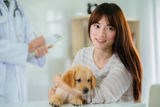 Donna sveglia con il cucciolo di golden retriever dal veterinario