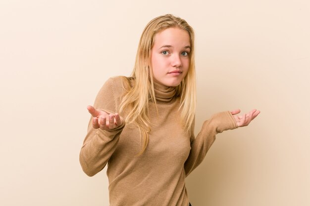 Donna sveglia e naturale dell'adolescente che dubita e che scrolla le spalle le spalle nel gesto interrogante.