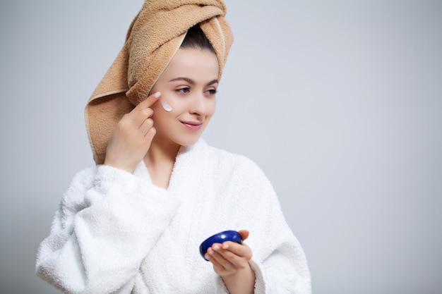 Donna sveglia in bagno che fa procedura cosmetica per cura di pelle facciale