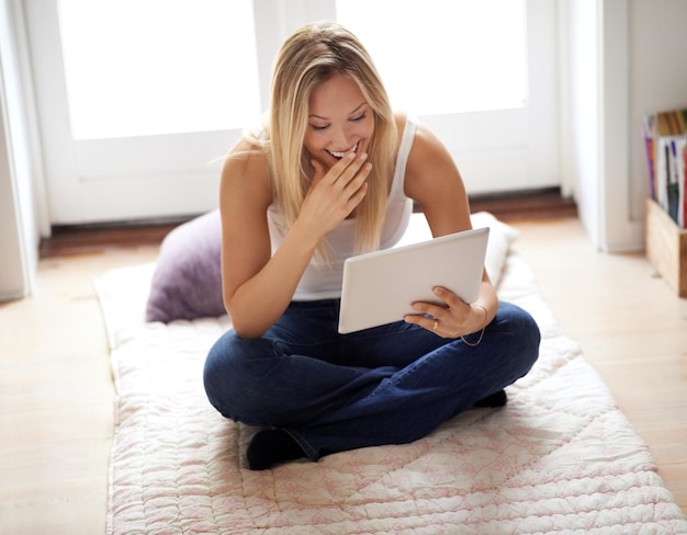 Donna tablet e ridere per i social media in casa seduta e pavimento per rilassarsi Persona femminile gesto e sorriso per scherzo divertente con la tecnologia per film online o servizio di streaming in salotto