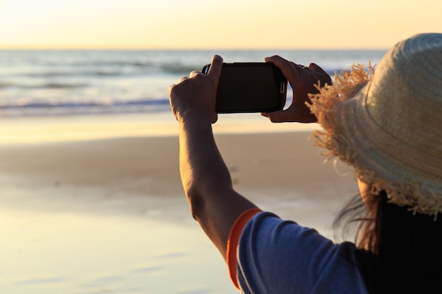 Donna tailandese che utilizza smartphone alla spiaggia