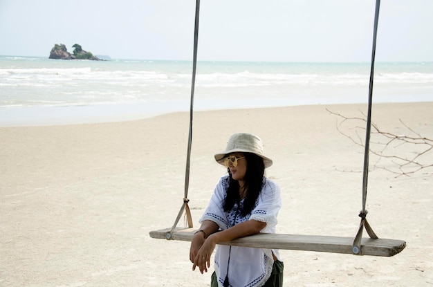 Donna tailandese stand e rilassarsi sulla panca di legno oscilla giocattolo a Laem Charoen Beach e Mae Pim Beach a Rayong Thailandia